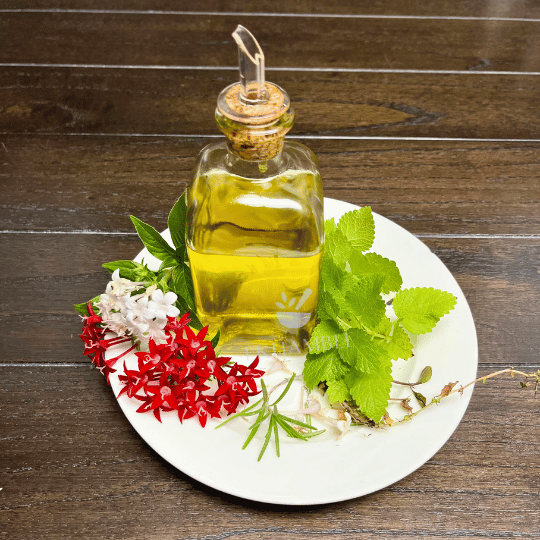 Freshly made rosemary and peppermint-infused hair oil with dried rose petals, ready for use on thinning hair