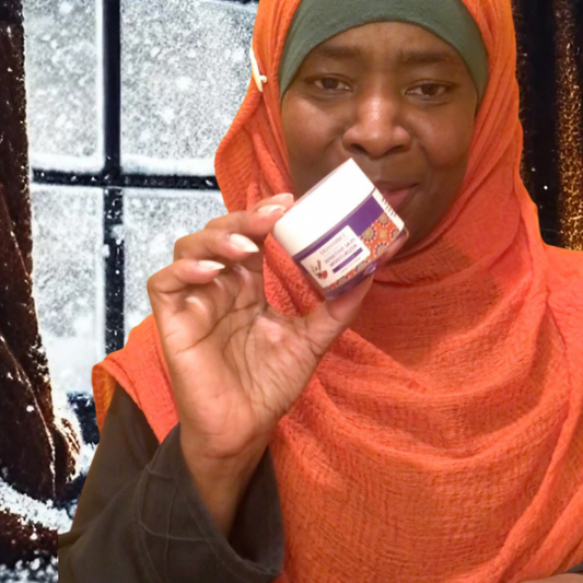 Woman with jar of Ekhambee Sensitive Skin Moisturizer next to winter window